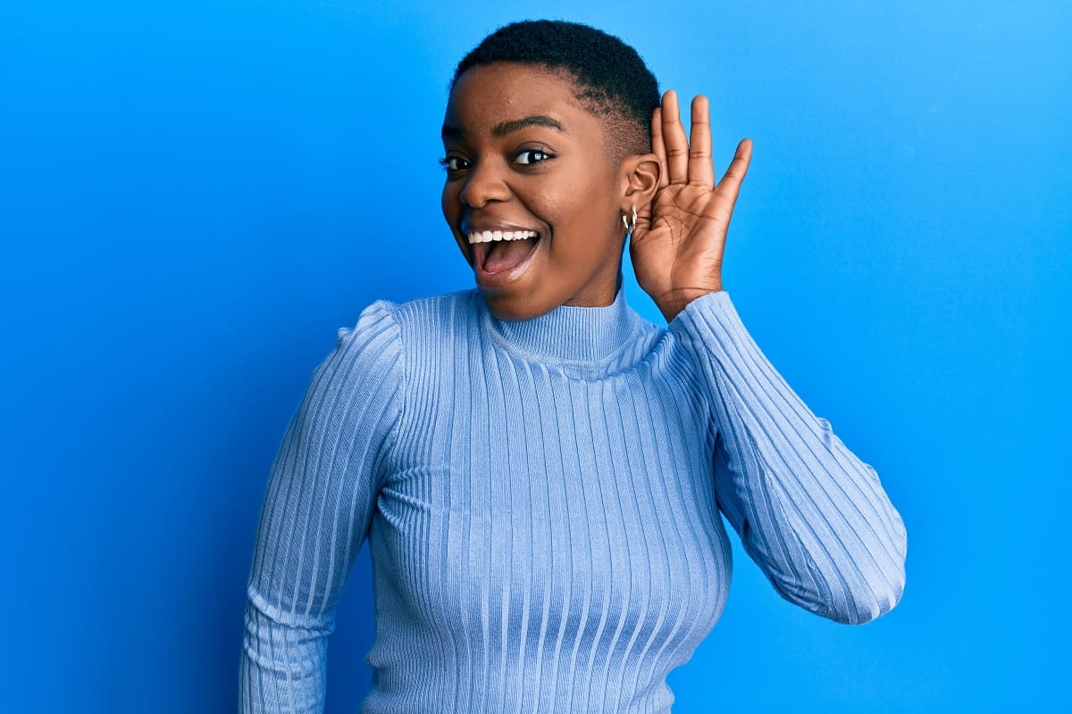 woman cupping ear to hear better while smiling